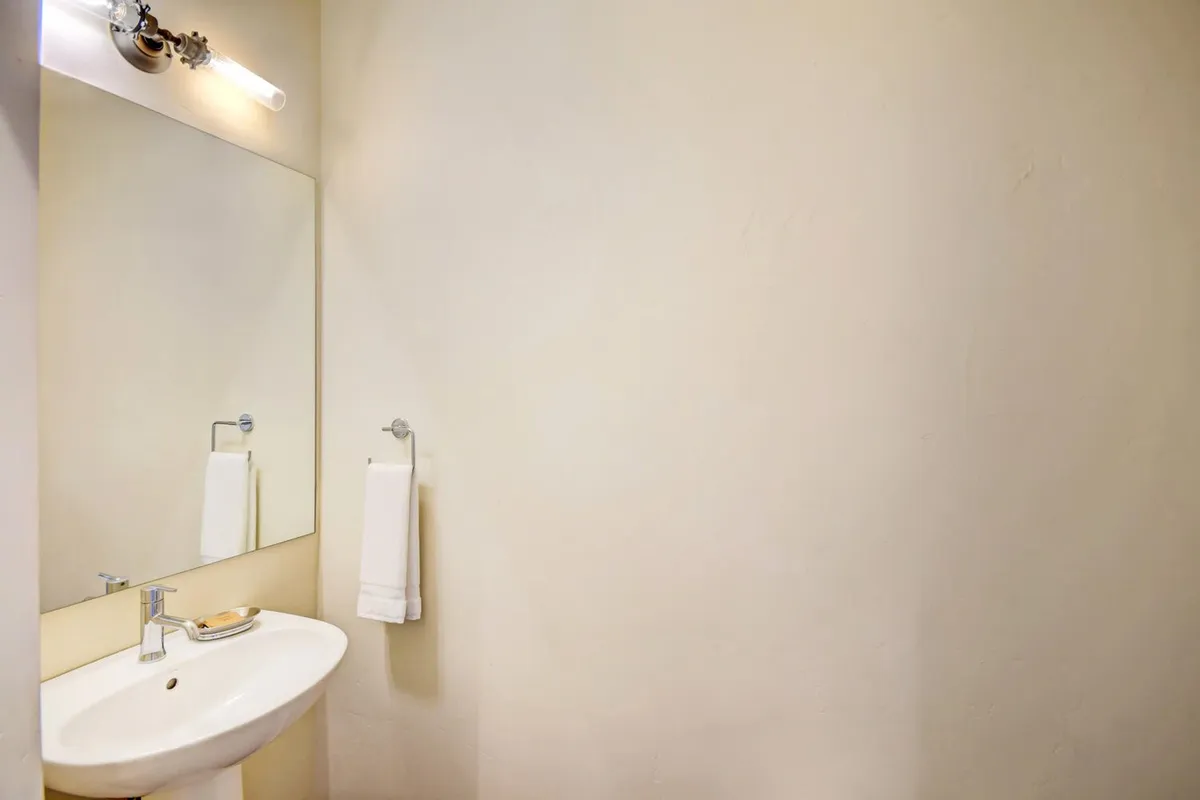 A modern, serene bathroom with a contemporary sink, mirror, and towel, all bathed in soft, calming light. The space is designed for moments of self-care and relaxation, echoing the spa-inspired amenities mentioned.