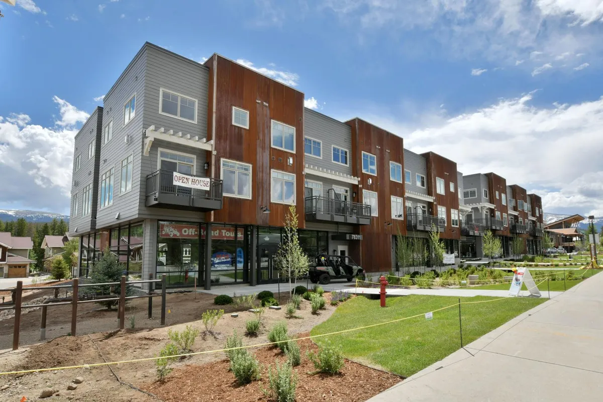 A modern exterior shot showcases the property’s contemporary architecture, complete with balconies and clear signage. The scene is welcoming and subtly hints at the social, community-oriented atmosphere of the area.