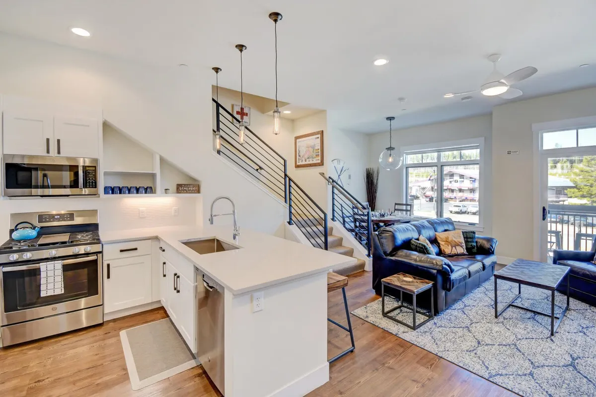 A spacious, open-plan interior featuring a modern kitchen, comfortable living area, and stylish staircase. The arrangement invites group gatherings, entertaining, and relaxation after a day out.